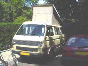 VW T3 camper met geopend hefdak en fiets er voor