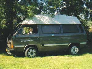 VW T3 camper onder bomen op een grasveld